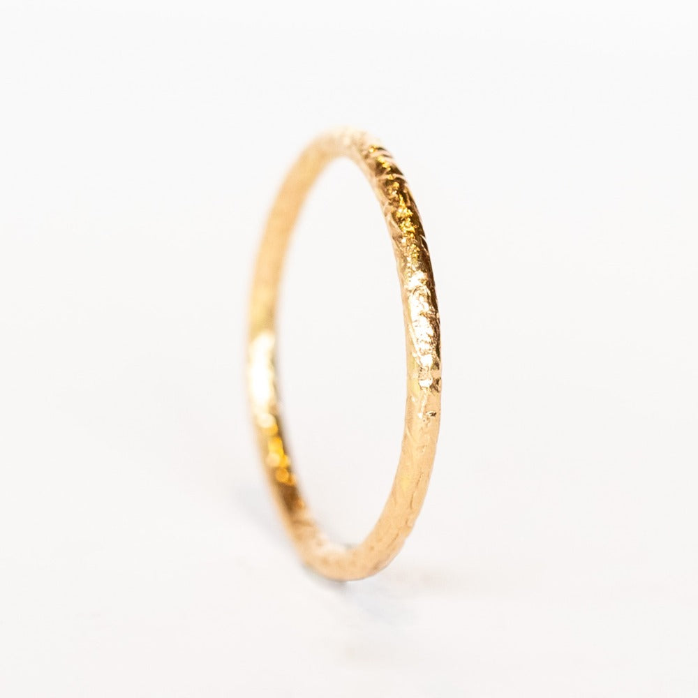 A thin, textured rose gold wedding band.