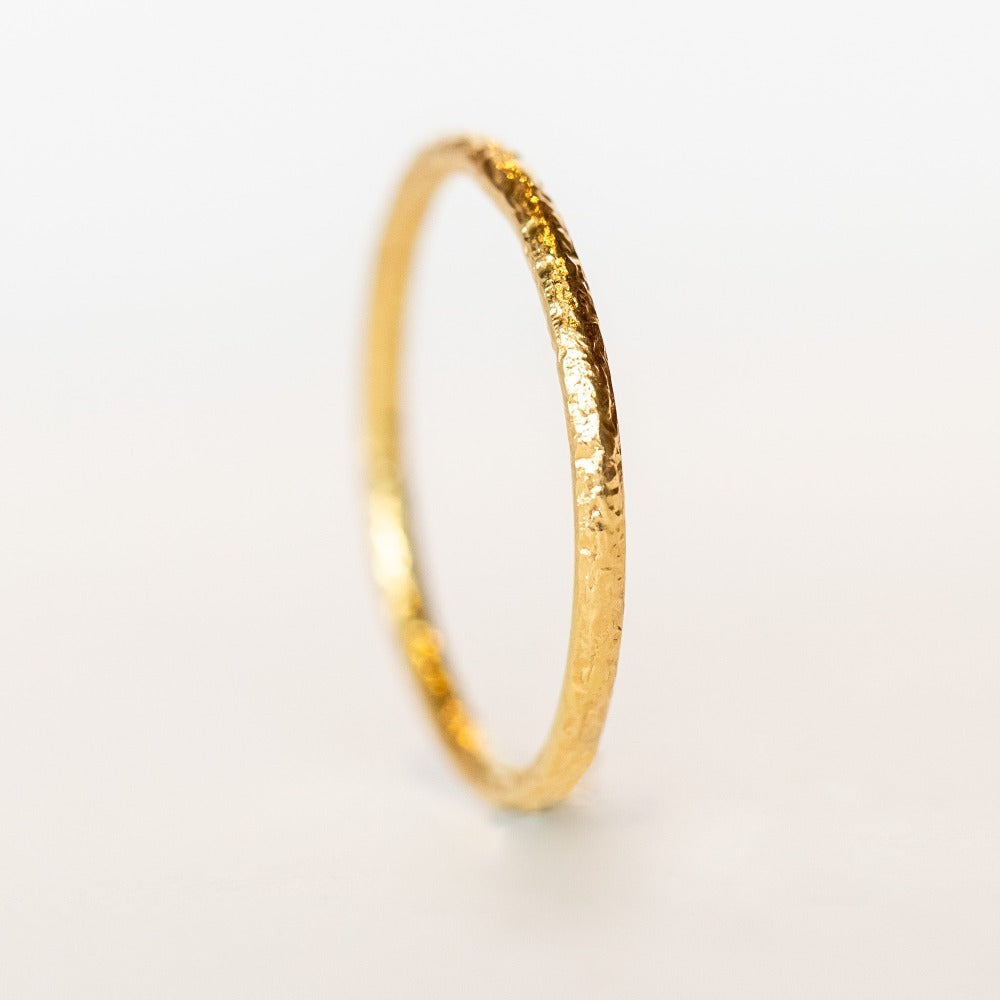 A hammered texture, thin yellow gold wedding band.