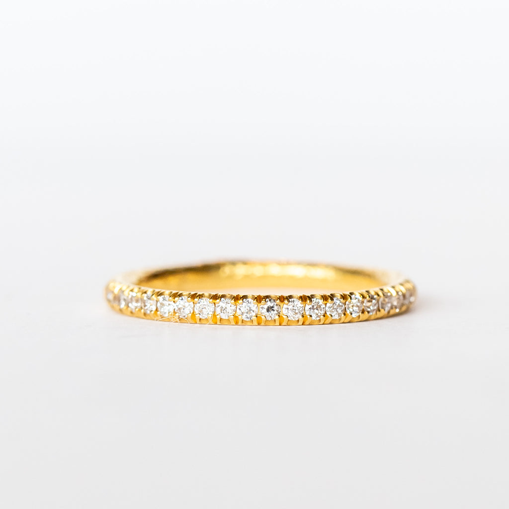 A textured gold wedding band with a row of French pave set diamonds around the top half.
