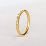 A textured gold wedding band with a row of French pave set diamonds around the top half.