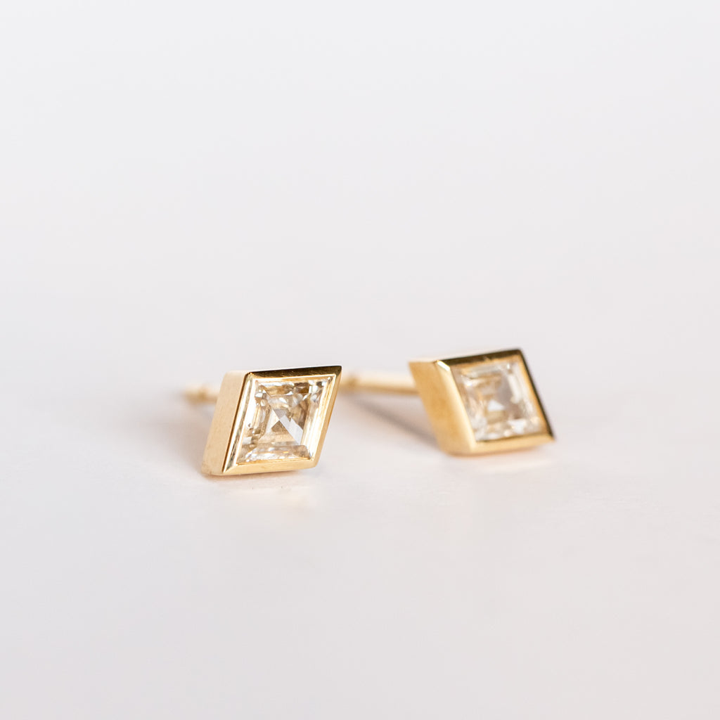 Lozenge (diamond shape) cut diamond stud earrings set in yellow gold bezels with post backs.