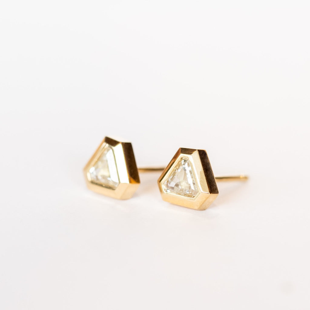 Triangular, lozenge cut diamonds bezel set in yellow gold stud earrings.