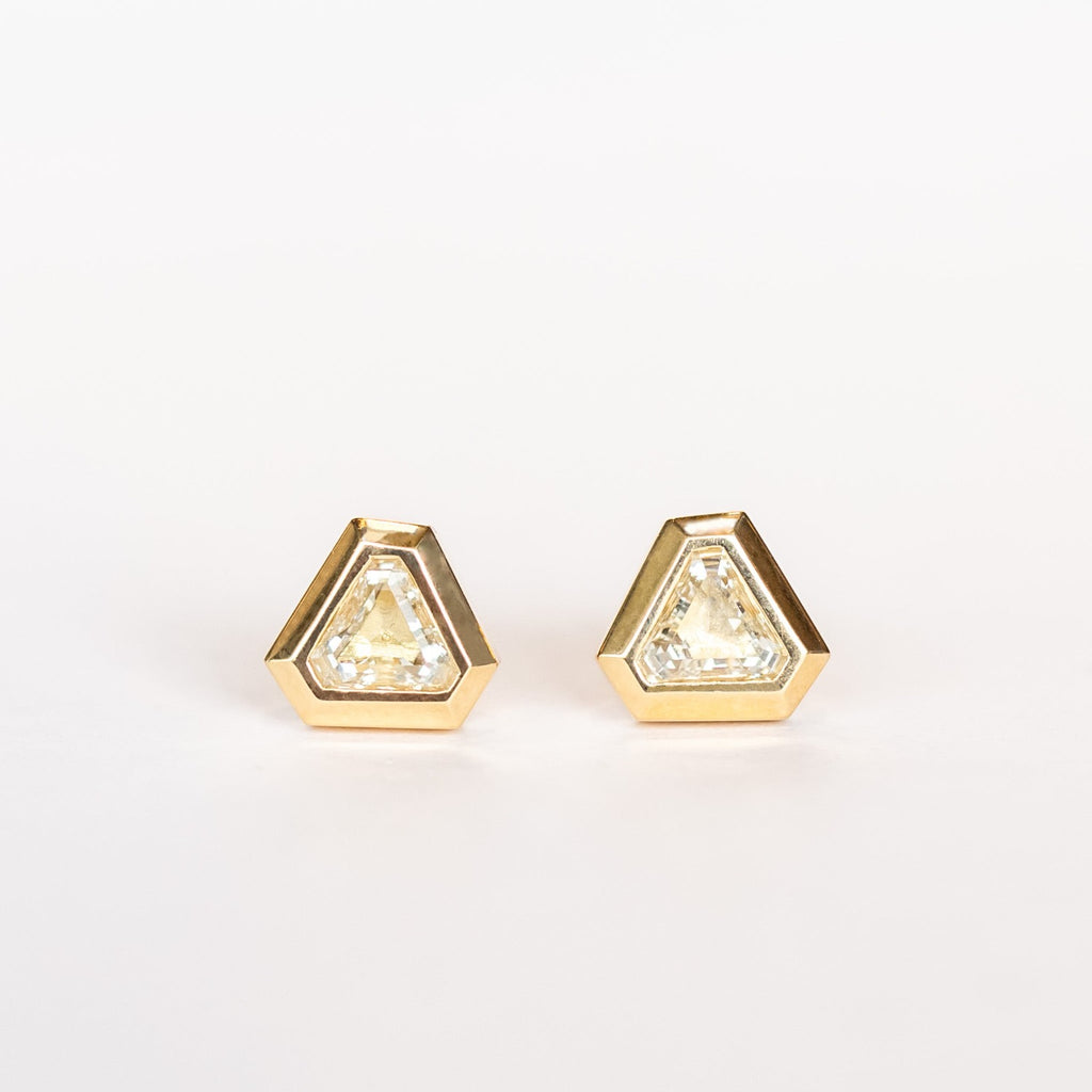 Triangular, lozenge cut diamonds bezel set in yellow gold stud earrings.