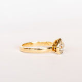 A pear-shaped diamond is bezel set in yellow gold on a solitaire engagement ring.