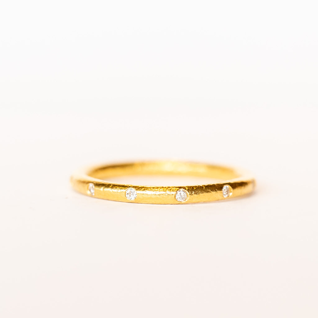 A bright yellow gold wedding band with spaced out diamonds all the way around.