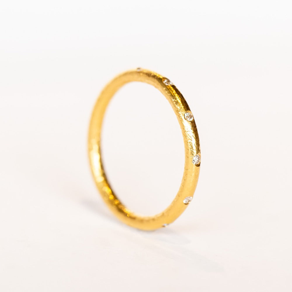 A bright yellow gold wedding band with spaced out diamonds all the way around.