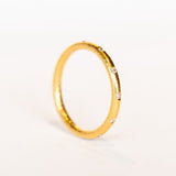 A bright yellow gold wedding band with spaced out diamonds all the way around.
