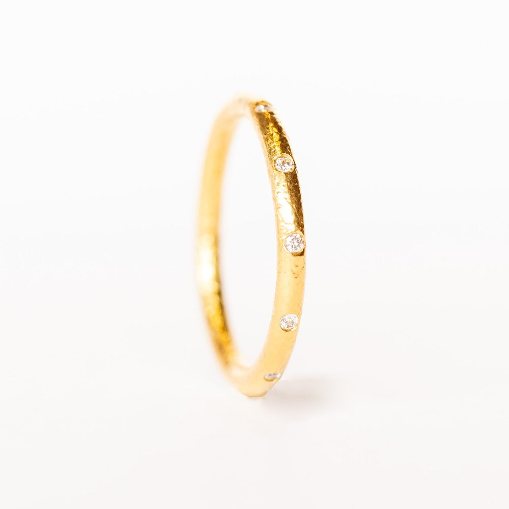 A bright yellow gold wedding band with spaced out diamonds all the way around.