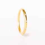 A bright yellow gold wedding band with spaced out diamonds all the way around.