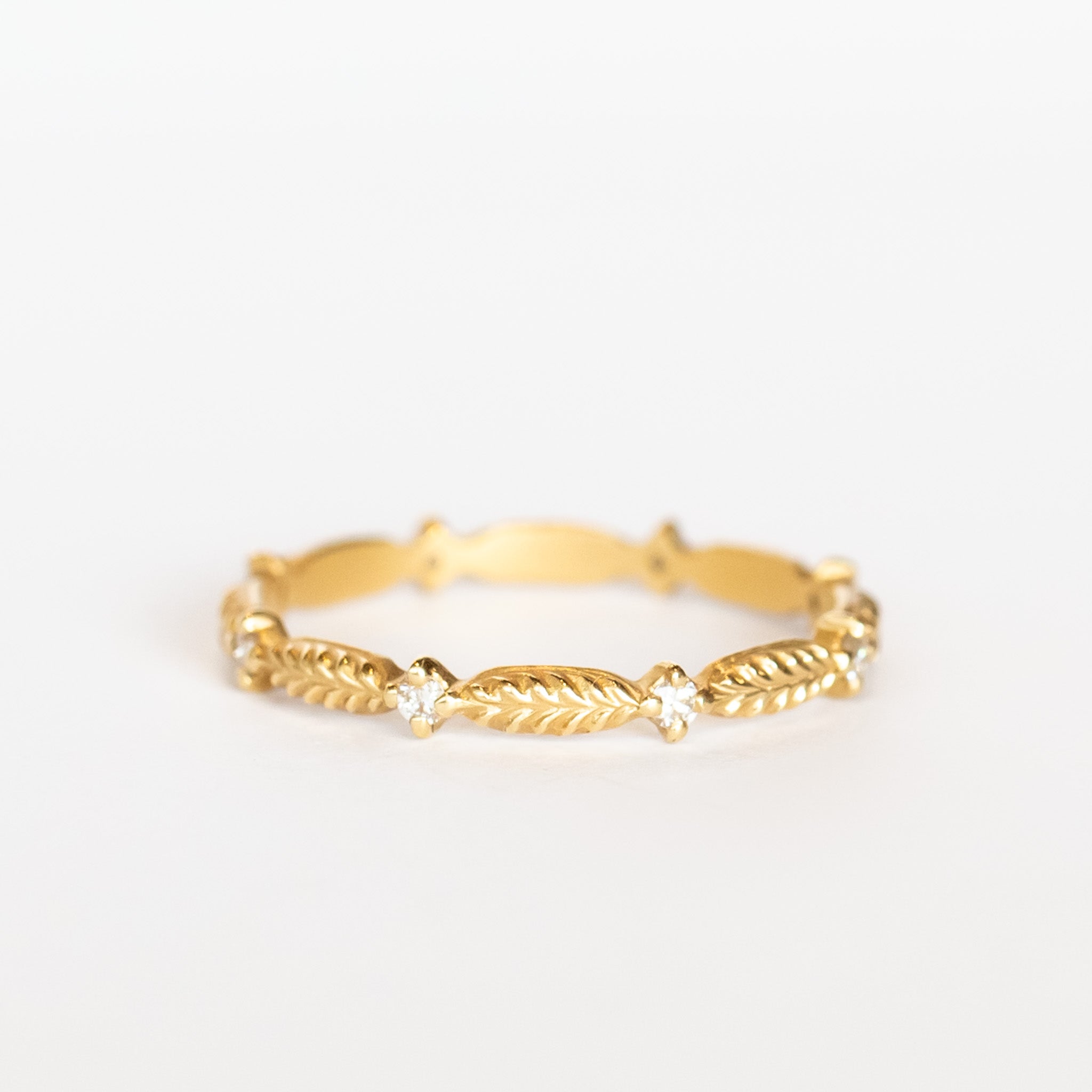 A yellow gold diamond eternity band with a leaf pattern interspersed with tiny diamonds.