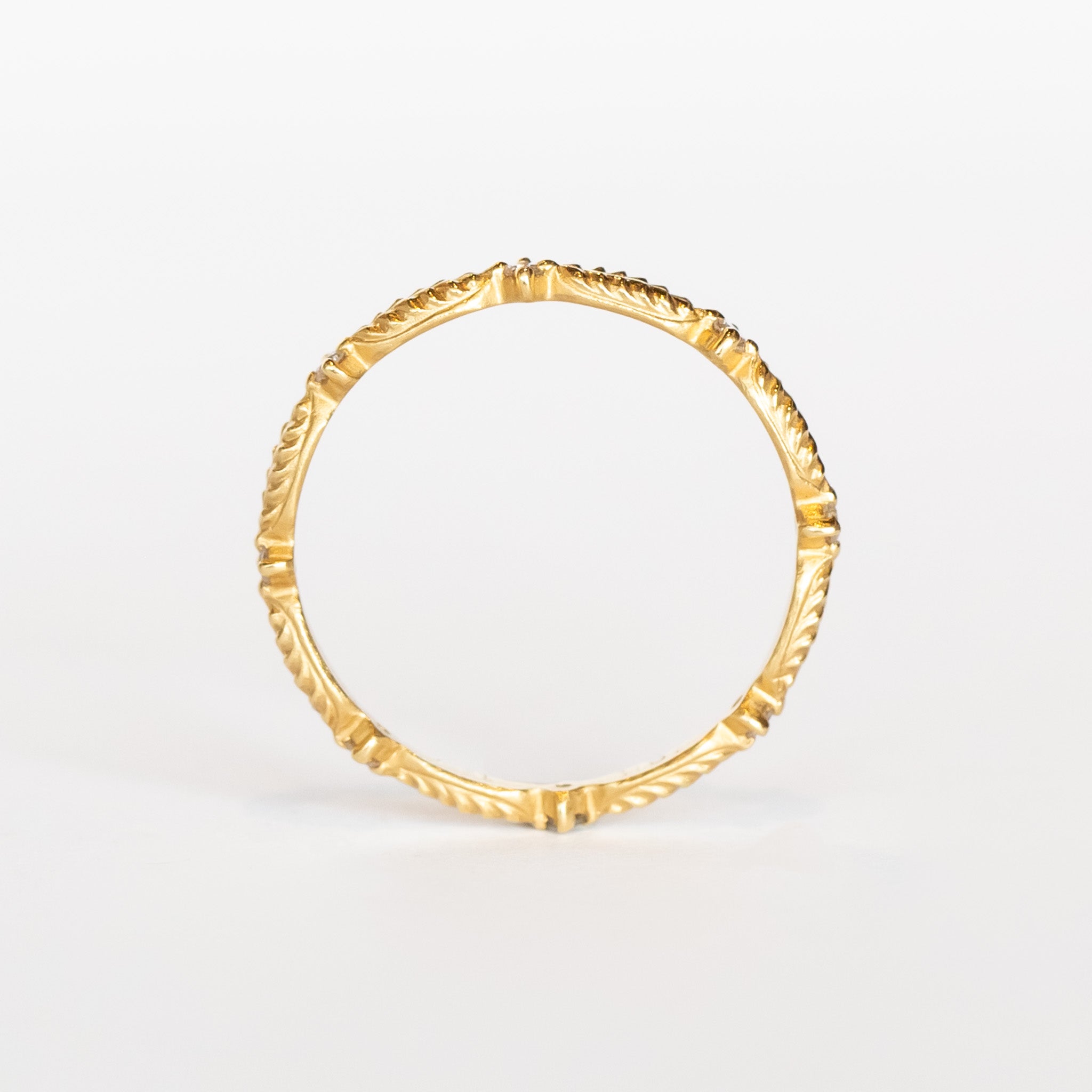 A yellow gold diamond eternity band with a leaf pattern interspersed with tiny diamonds.