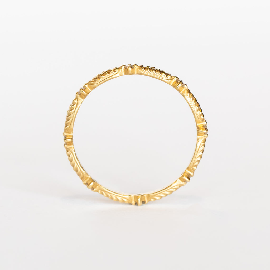 A yellow gold diamond eternity band with a leaf pattern interspersed with tiny diamonds.