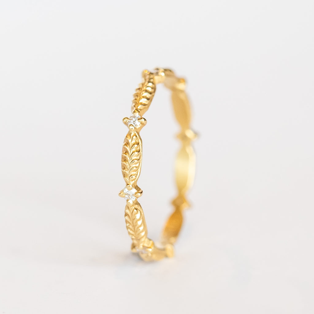 A yellow gold diamond eternity band with a leaf pattern interspersed with tiny diamonds.
