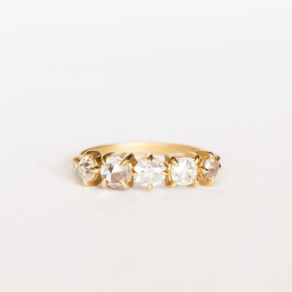 A yellow gold wedding band featuring five mixed-cut diamonds prong set with leaf-like accents on each side.