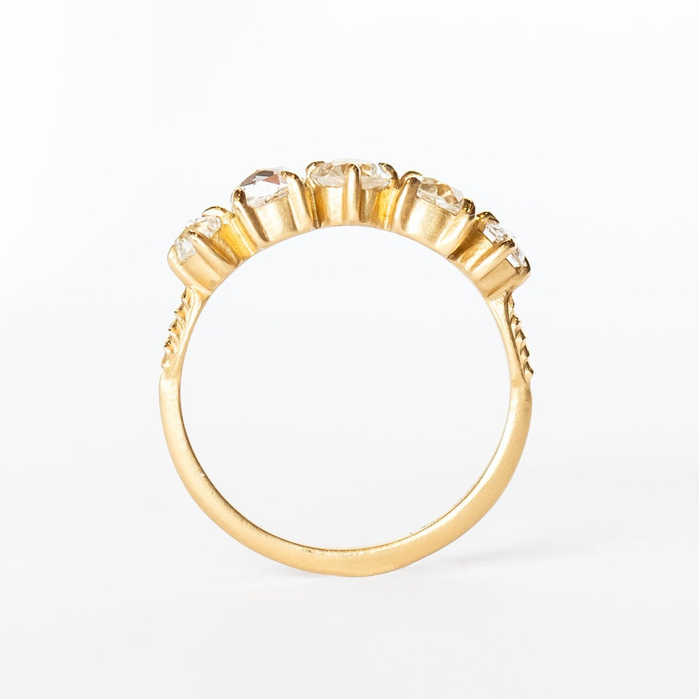 A yellow gold wedding band featuring five mixed-cut diamonds prong set with leaf-like accents on each side.