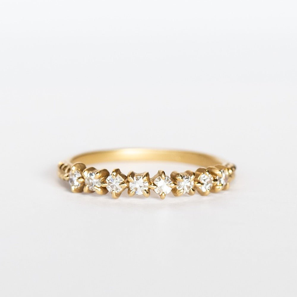 A yellow gold band featuring a row of 9 single-cut white diamonds set with alternating direction prongs.