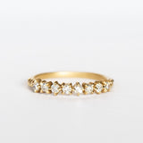 A yellow gold band featuring a row of 9 single-cut white diamonds set with alternating direction prongs.
