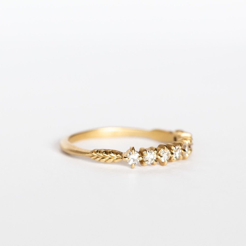 A yellow gold band featuring a row of 9 single-cut white diamonds set with alternating direction prongs.