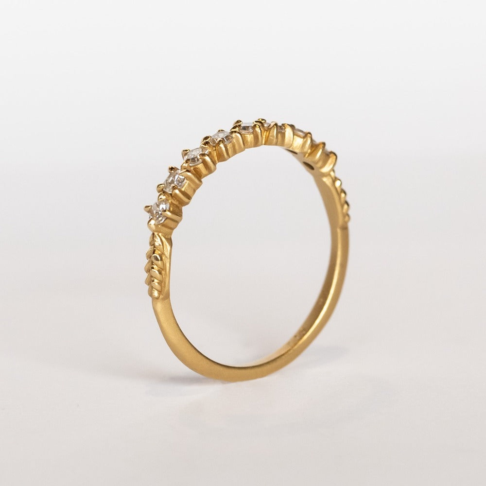 A yellow gold band featuring a row of 9 single-cut white diamonds set with alternating direction prongs.