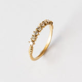 A yellow gold band featuring a row of 9 single-cut white diamonds set with alternating direction prongs.
