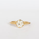 A yellow gold solitaire diamond engagement ring featuring a prong set old european cut diamond and a slender matte finish, leaf accented band.