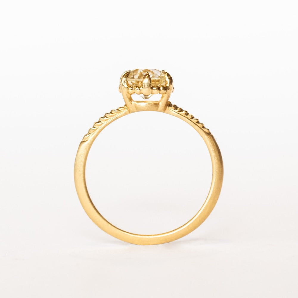 A yellow gold solitaire diamond engagement ring featuring a prong set old european cut diamond and a slender matte finish, leaf accented band.