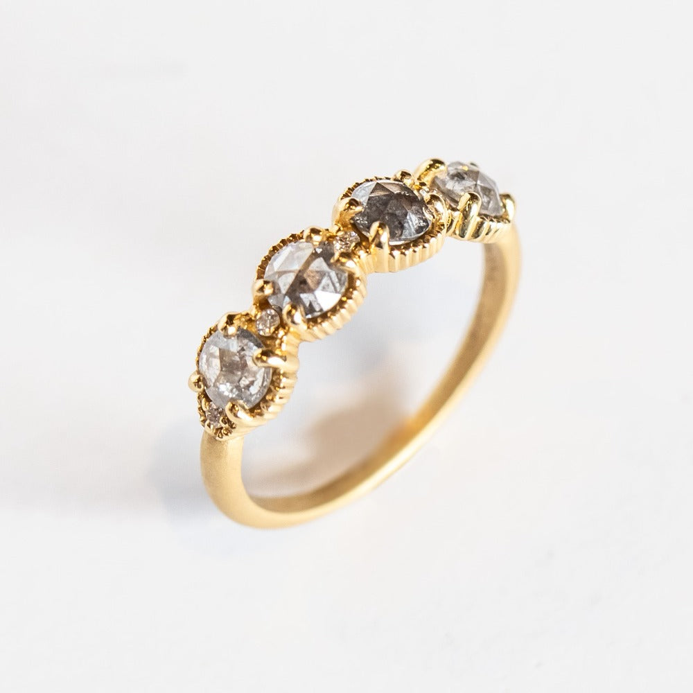 Four rose cut salt and pepper diamonds are set into a yellow gold band with beaded edge details.
