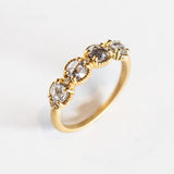 Four rose cut salt and pepper diamonds are set into a yellow gold band with beaded edge details.