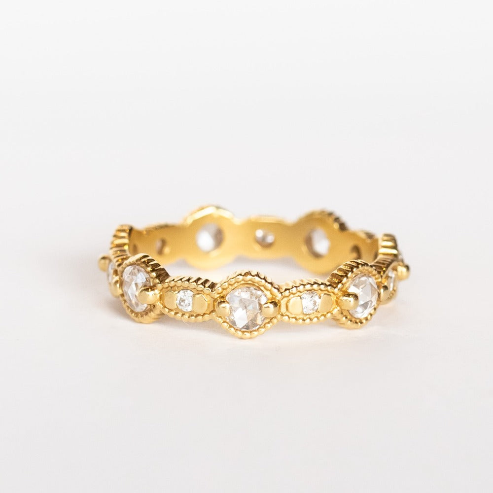 A yellow gold eternity band featuring round rose cut diamonds alternating with tiny brilliant round white diamonds. The alternating round and oval settings are accented with milgrain bed details.