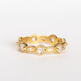 A yellow gold eternity band featuring round rose cut diamonds alternating with tiny brilliant round white diamonds. The alternating round and oval settings are accented with milgrain bed details.