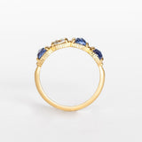 A yellow gold band set with three rose cut blue sapphires and one rose cut diamond. There are tiny white diamonds in between each stone and the settings are edged with bead details.