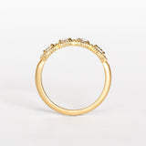 A yellow gold band set with four round rose cut white diamonds alternating with tiny brilliant white diamonds. The edges of the setting have bead details.