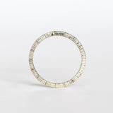A white gold wedding band with a seed-shaped pattern all the way around. The edges have milgrain beading.