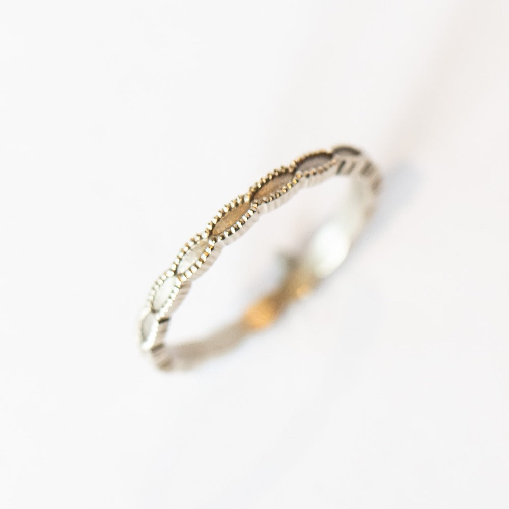 A white gold wedding band with a seed-shaped pattern all the way around. The edges have milgrain beading.