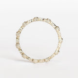 A white gold eternity wedding band featuring leaf patterns alternating with tiny bezel set diamonds surrounded with milgrain dot accents.