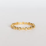A yellow gold diamond eternity wedding band featuring leaf pattern accents alternating with bezel set diamonds with milgrain dot edges.