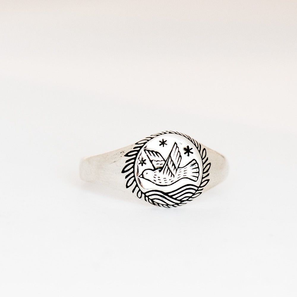 A small signet ring with a bird engraving over waves, with stars and a wreath.