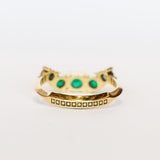 An emerald ring set of engagement ring and wedding band. Features an emerald cut emerald gemstone center flanked by six round emeralds, and a graduating size emerald band that contours to fit.