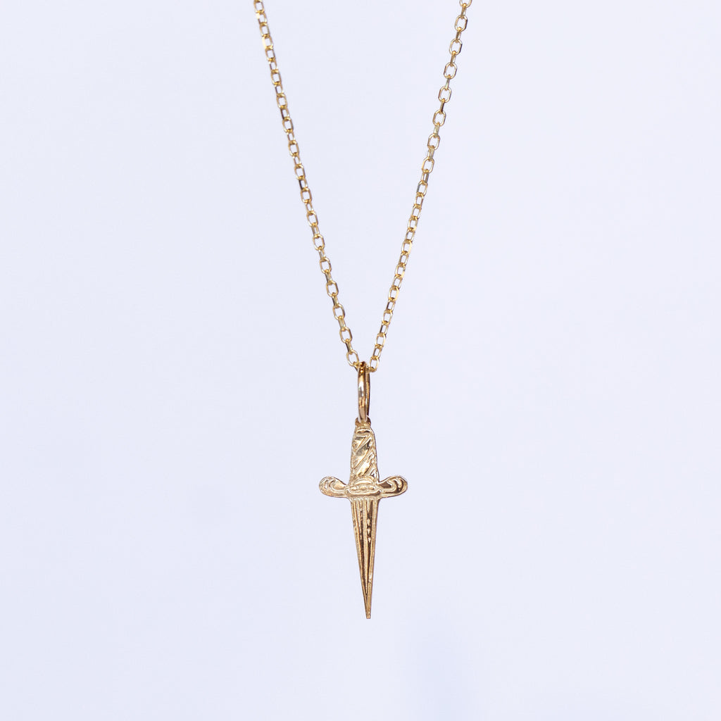 A tiny gold engraved dagger pendant necklace.