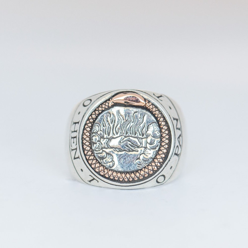 A silver signet ring with a rose gold ouroboros snake surrounding shaking hands and flames with the engraving of the words 'Hen To Pan' encircle to the edge of the ring which translate to 'One Is The All