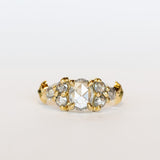 A diamond engagement ring featuring salt and pepper diamonds, an oval at the center, flanked by clusters of three smaller diamonds on each side, set in 18 karat yellow gold.