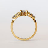 A diamond engagement ring featuring salt and pepper diamonds, an oval at the center, flanked by clusters of three smaller diamonds on each side, set in 18 karat yellow gold.