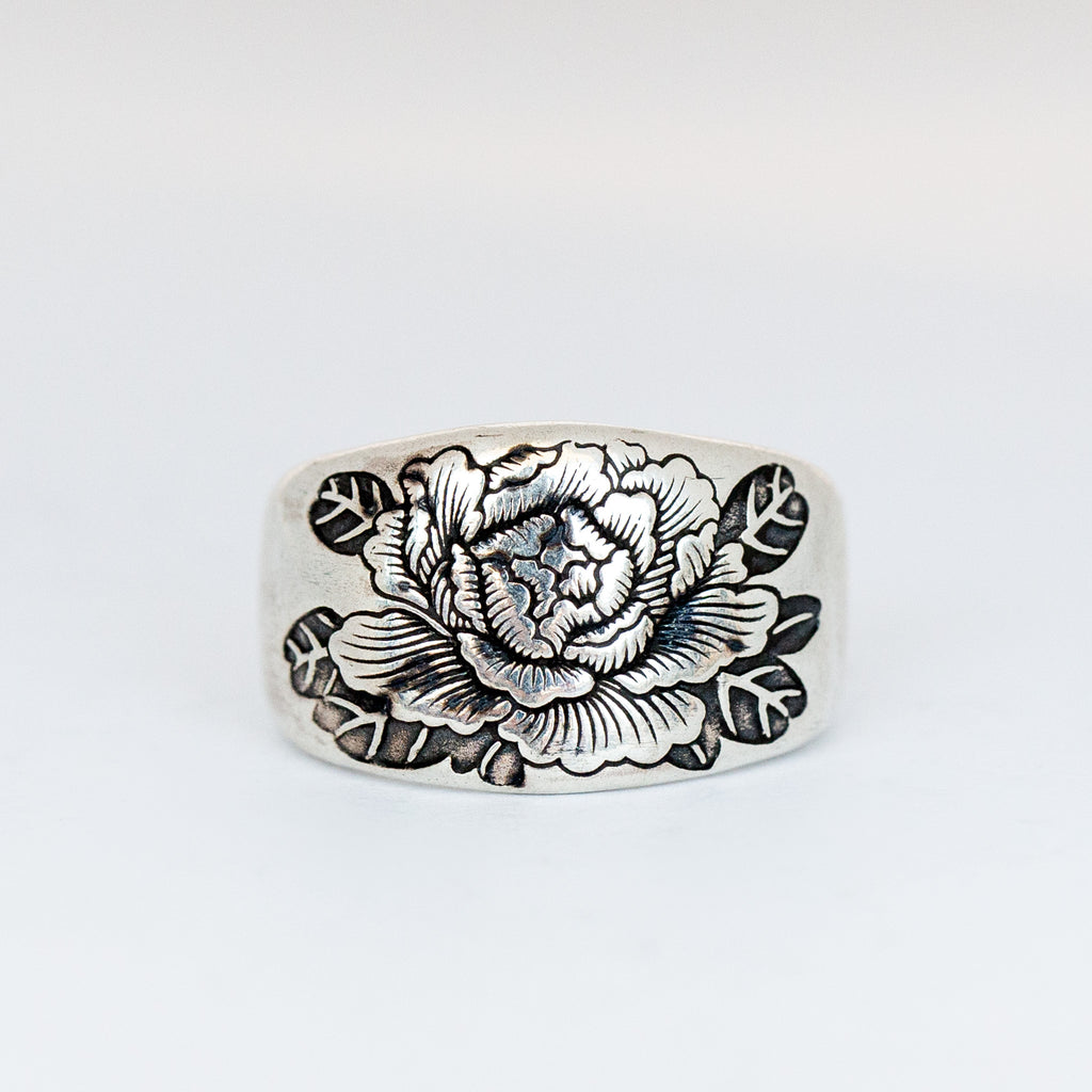 A chunky silver signet ring with engraved peony design.