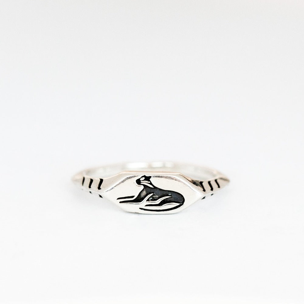 A dainty silver signet ring with a lounging cat engraving.