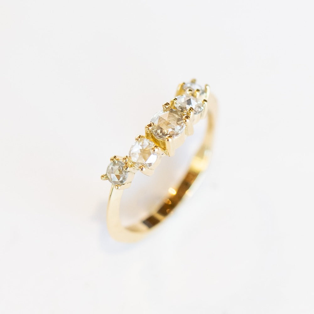 A diamond contour wedding band featuring five graduated size rose cut diamonds set in 18 karat yellow gold.