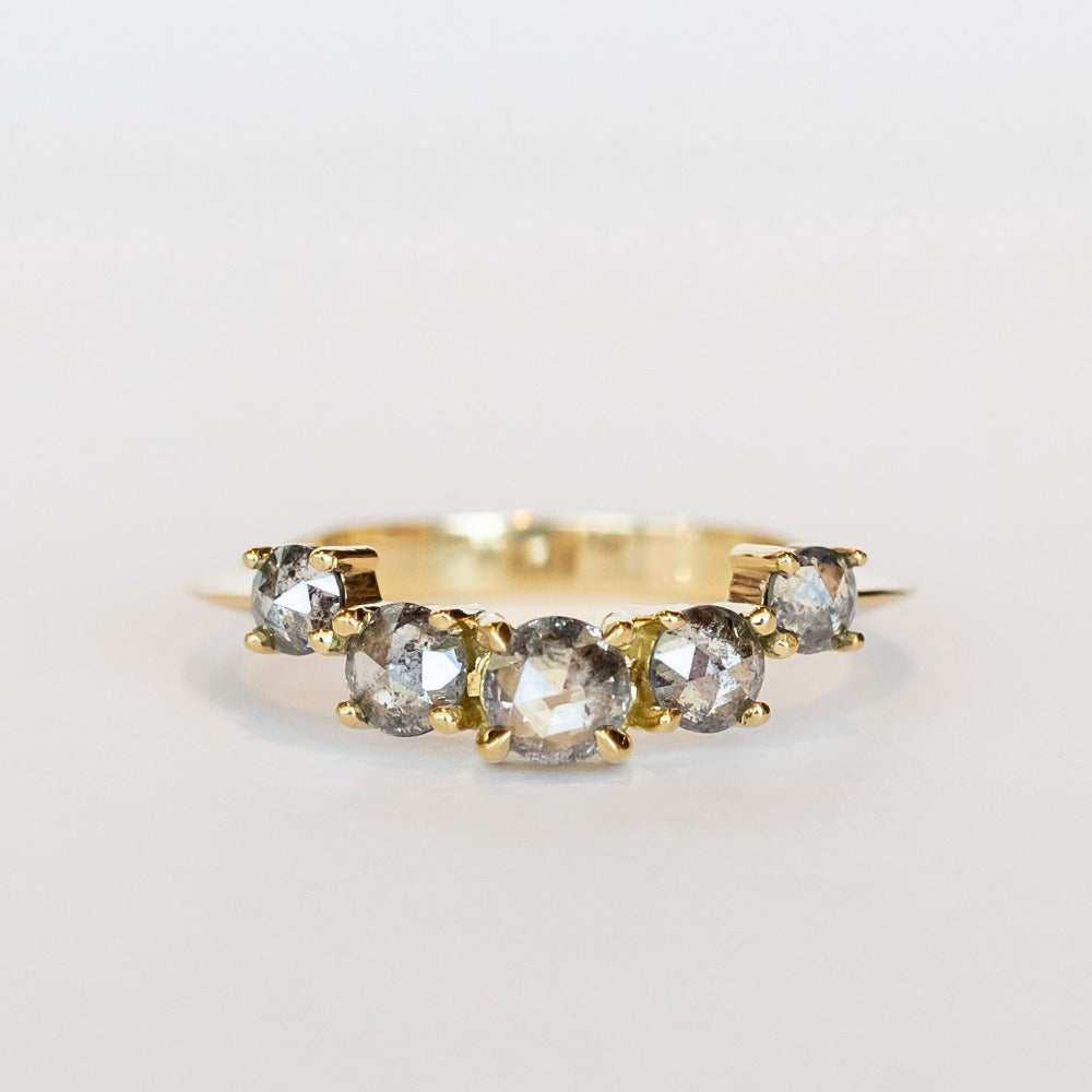A curved diamond contour band crafted in 18 karat yellow gold, set with five graduated size, rose cut, salt and pepper diamonds.