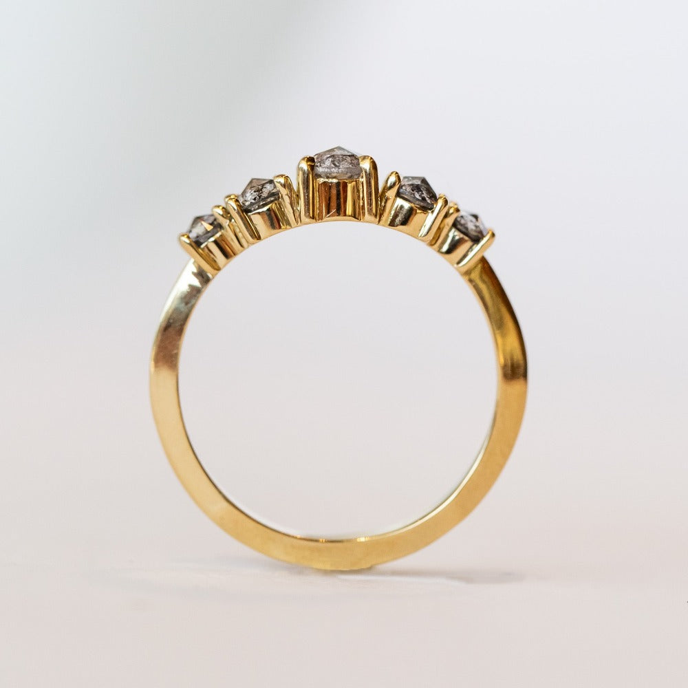 A curved diamond contour band crafted in 18 karat yellow gold, set with five graduated size, rose cut, salt and pepper diamonds.