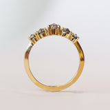 A curved diamond contour band crafted in 18 karat yellow gold, set with five graduated size, rose cut, salt and pepper diamonds.
