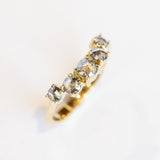 A curved diamond contour band crafted in 18 karat yellow gold, set with five graduated size, rose cut, salt and pepper diamonds.