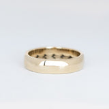 Domed gold wedding band featuring a wave pattern engraving that wraps all the way around the inside.